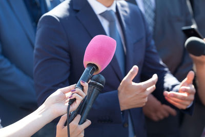 Cropped hand of journalist holding microphone in front of businessman