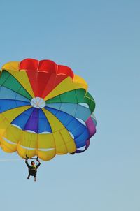 Low angle view of man parasailing against clear blue sky