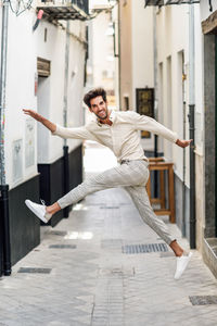 Portrait of happy man jumping in alley