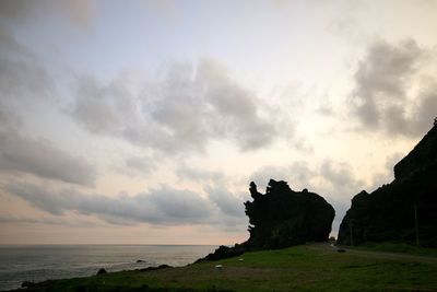 Scenic view of cliff by sea against sky