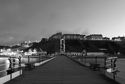 Pier over sea against sky in city