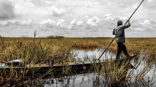 Full length of man fishing in lake against sky