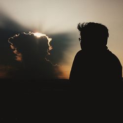 Silhouette of woman against sky at sunset