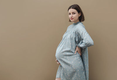 Young woman standing against wall