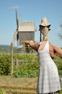 Scarecrow on field against traditional windmill