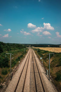 Empty railroad tracks on field against sky