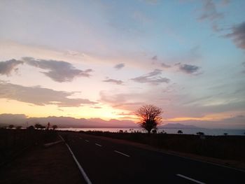 Road by silhouette landscape against sky during sunset