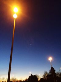 Low angle view of illuminated trees against blue sky