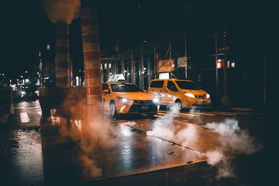 Cars on illuminated city against sky at night