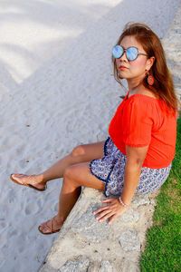 Young woman sitting on sunglasses at beach