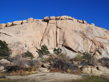 Low angle view of rocks against clear blue sky