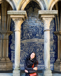 A girl in porto standing in cloister with authentic azulejos on the wall and decorative stone arches