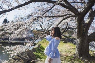 Full length of woman standing by tree