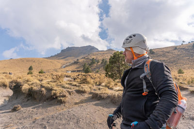 Man looking away while standing against mountain