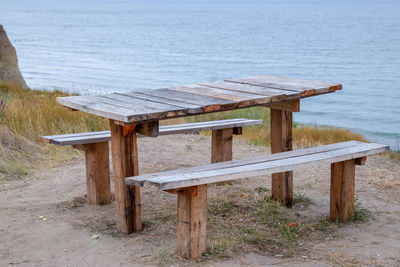 Empty benches and table by sea