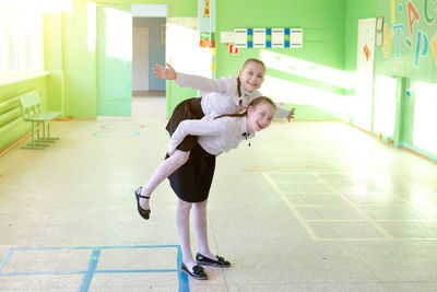 Portrait of girl carrying sister on back at classroom