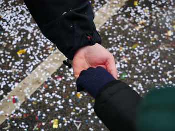 Cropped image of friends holding hands over confetti