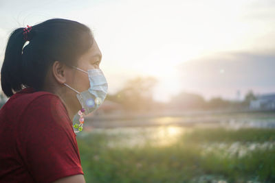 Side view of woman against sky during sunset