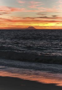 Scenic view of sea against dramatic sky during sunset