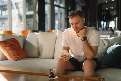 Young man using mobile phone while sitting at home