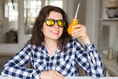 Woman holding juice while wearing sunglasses