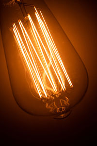 Close-up of illuminated light bulb against black background
