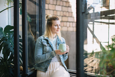 Woman having coffee while sitting at window