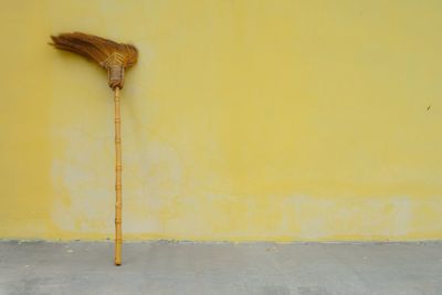 The broom leaned against the yellow wall