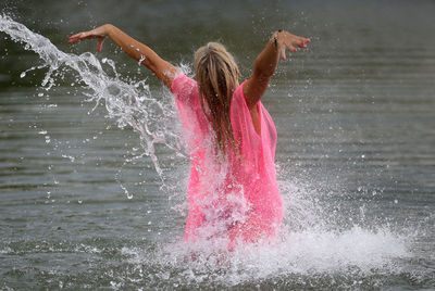 Rear view of woman splashing water