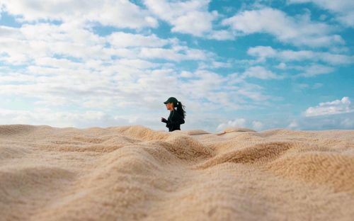 Man on sand dune in desert against sky