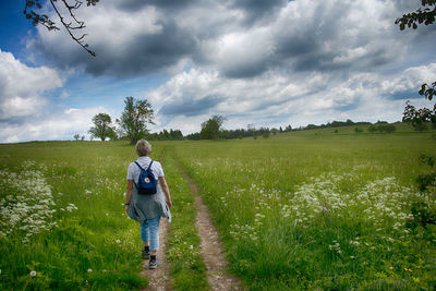 Rear view of man on field against sky