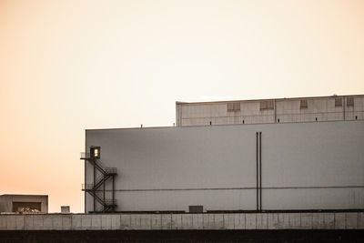 Low angle view of factory against sky at sunset