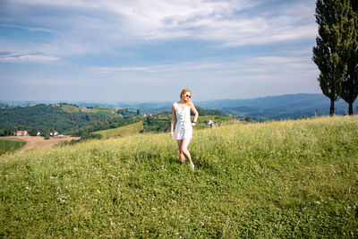 Full length of woman standing on field against sky