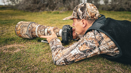 Side view of man using mobile phone on field