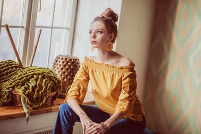 Young woman looking away while sitting at home