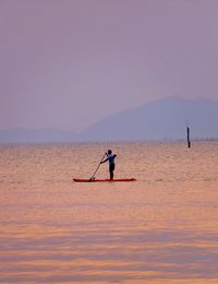 Man rowing boat in sea against clear sky