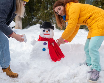 Two caucasian women are making a snowman. winter fun