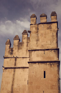 Low angle view of old building against cloudy sky