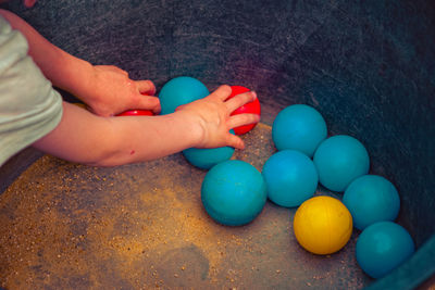 Midsection of boy playing with balls in container