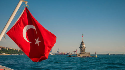Turkish flag waving over the bosphorus strait in istanbul with the maiden's tower in the background 