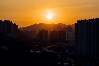 Modern buildings in city against sky during sunset