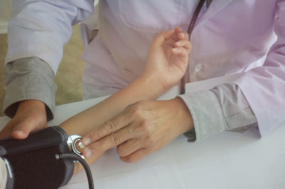 Midsection of doctor examining patient arm with stethoscope