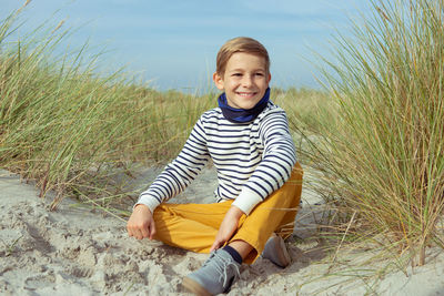 Smiling boy sitting on sand at beach