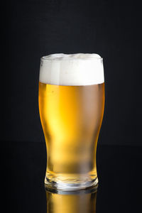 Close-up of beer glass against black background