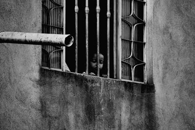 Woman standing by window of old building