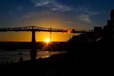 Silhouette of bridge over sea during sunset