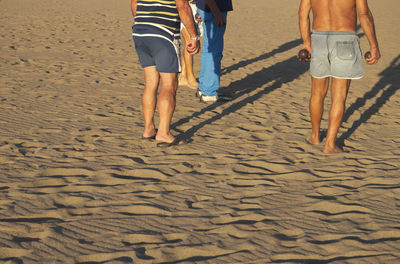Low section of men standing at beach