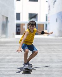 Full length of boy skateboarding on street