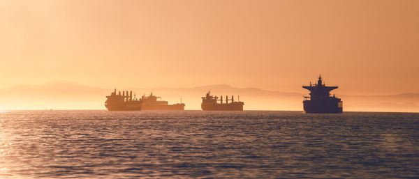 Silhouette ship in sea against sky during sunset