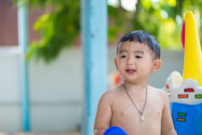 Portrait of shirtless boy looking at swimming pool